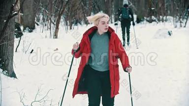 一位身穿红<strong>羽绒服</strong>的年轻金发女子在森林里滑雪-冬季活动